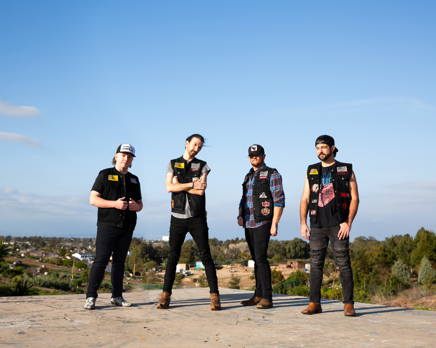 Four members of the Redneck Rodeo band with a clear blue sky in the background.
